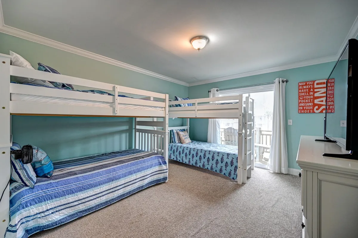 A playful and cozy bunkroom designed for children, this image features bunk beds, a single bed, colorful wall art, and a TV. The space is bright and inviting, with plenty of room for kids to play and unwind, perfectly matching the description of a cheerful, entertainment-equipped bunkroom paradise.
